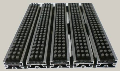 Zerbino tecnico composto da profili portanti in alluminio estruso antitorsione corredati da apposita guarnizione fonoassorbente nel lato inferiore. Parte di calpestio composta da spazzole a listello allineate parallelamente resistente alle intemperie Zerbino adatto al posizionamento in ambiente interno ed esterno. Base alluminio mm 8/13/17 