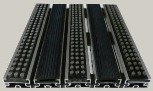 Zerbino tecnico composto da profili portanti in alluminio estruso antitorsione corredati da apposita guarnizione fonoassorbente nel lato inferiore. Cerniere drenanti e piene per permettere l ‘aspirazione senza sollevare lo zerbino. Parte di calpestio composta da gomma EPDM millerighe e spazzole in Nylon
						Zerbino adatto al posizionamento in ambiente esterno. Base alluminio mm 8/13/17 