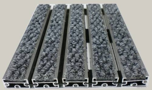 Zerbino tecnico composto da profili portanti in alluminio estruso antitorsione corredati da apposita guarnizione fonoassorbente nel lato inferiore. Cerniere drenanti e piene per permettere l ‘aspirazione senza sollevare lo zerbino. Parte di calpestio composta da tessile imputrescibile in polipriopilene 100%
						Zerbino adatto al posizionamento in ambiente interno ed esterno coperto. Base alluminio mm 8/13/17 